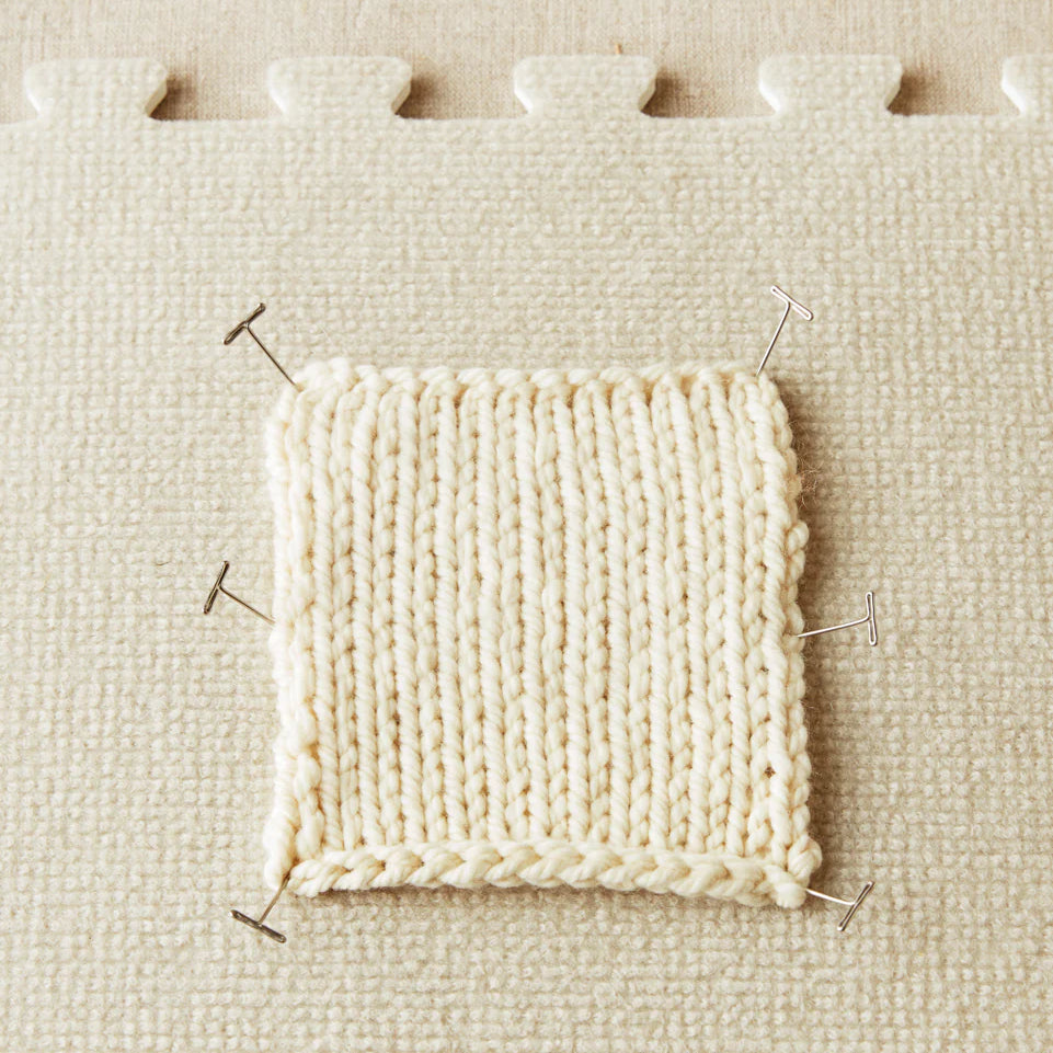 Knitted sample pinned to a fabric surface