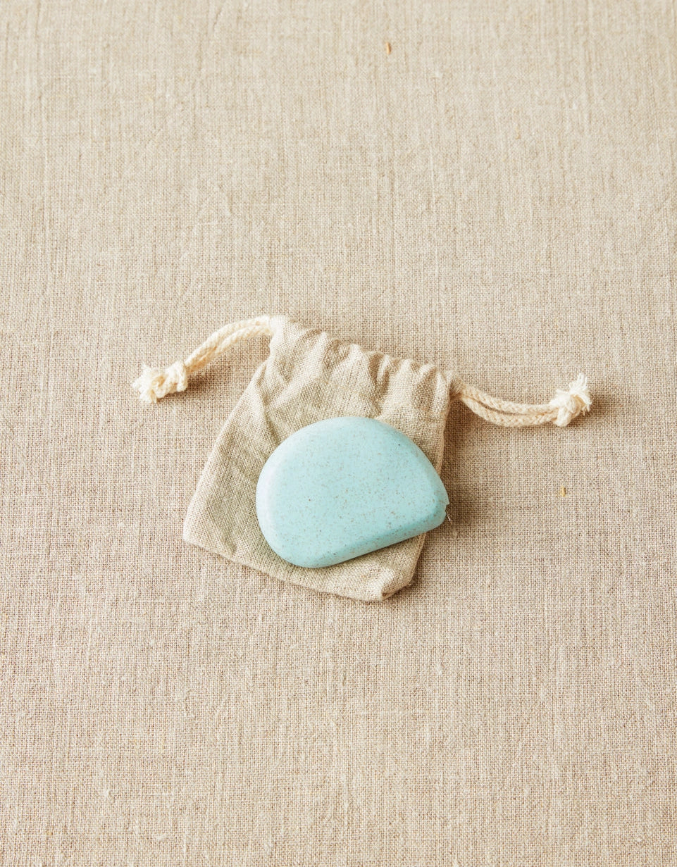 Blue colored tape measure in a drawstring bag on a beige fabric background