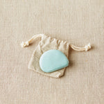 Blue colored tape measure in a drawstring bag on a beige fabric background