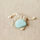 Blue colored tape measure in a drawstring bag on a beige fabric background
