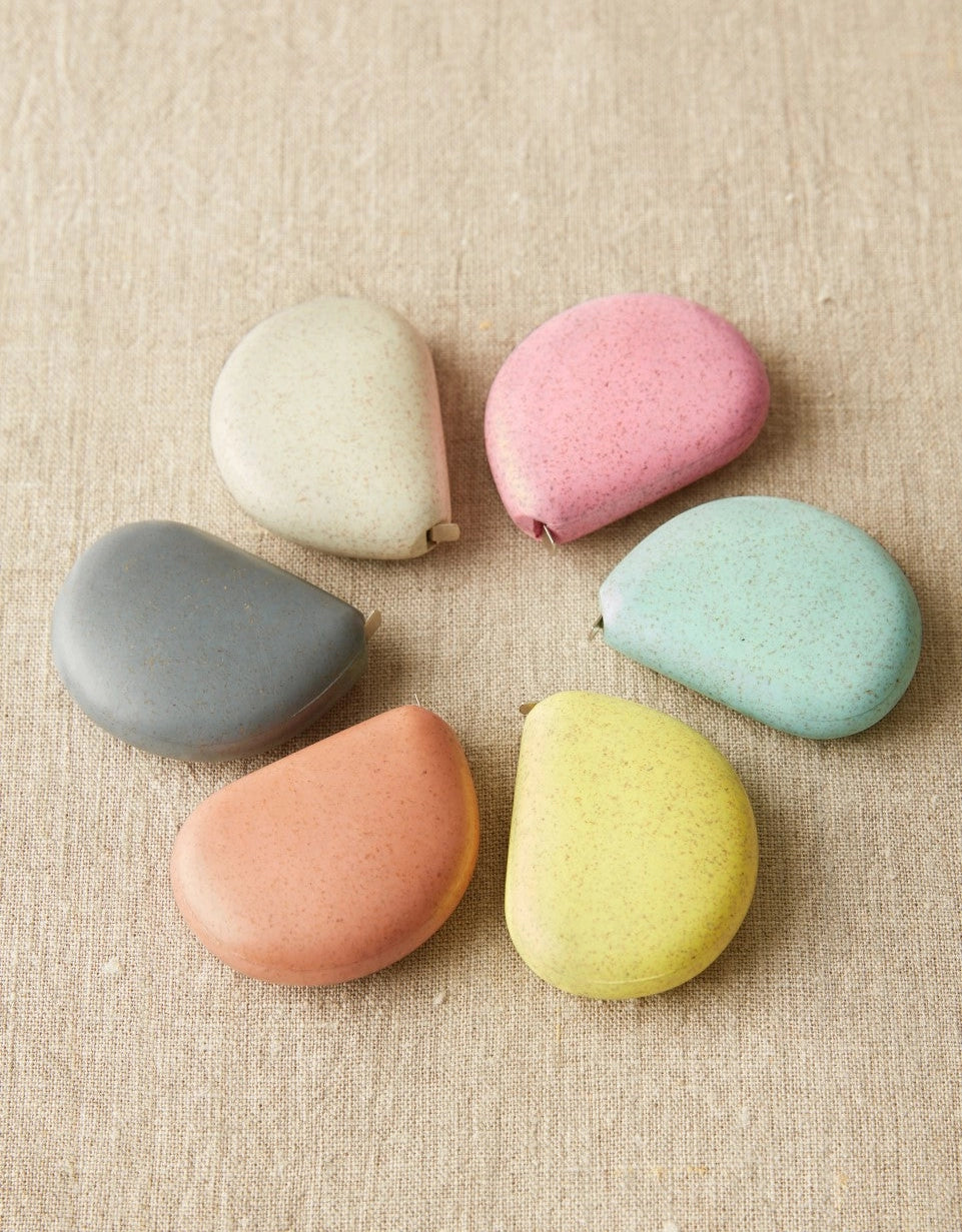 Set of colorful tape measures on a textured beige surface