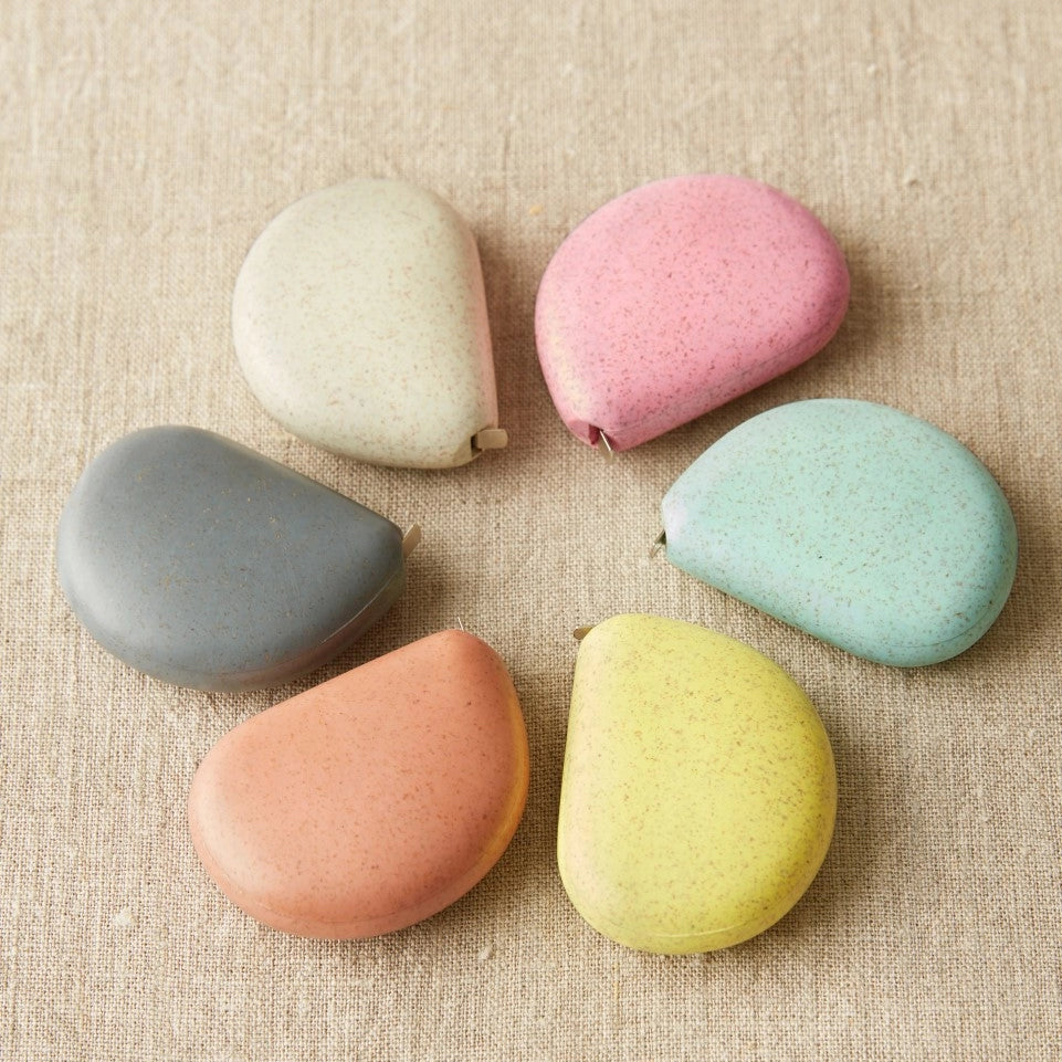 Set of colorful tape measures on a textured beige surface