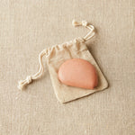 Clay colored tape measure on drawstring bag on a beige fabric background