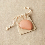 Clay colored tape measure on drawstring bag on a beige fabric background