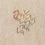 Set of geometric triangle-shaped stitch markers on a beige fabric background