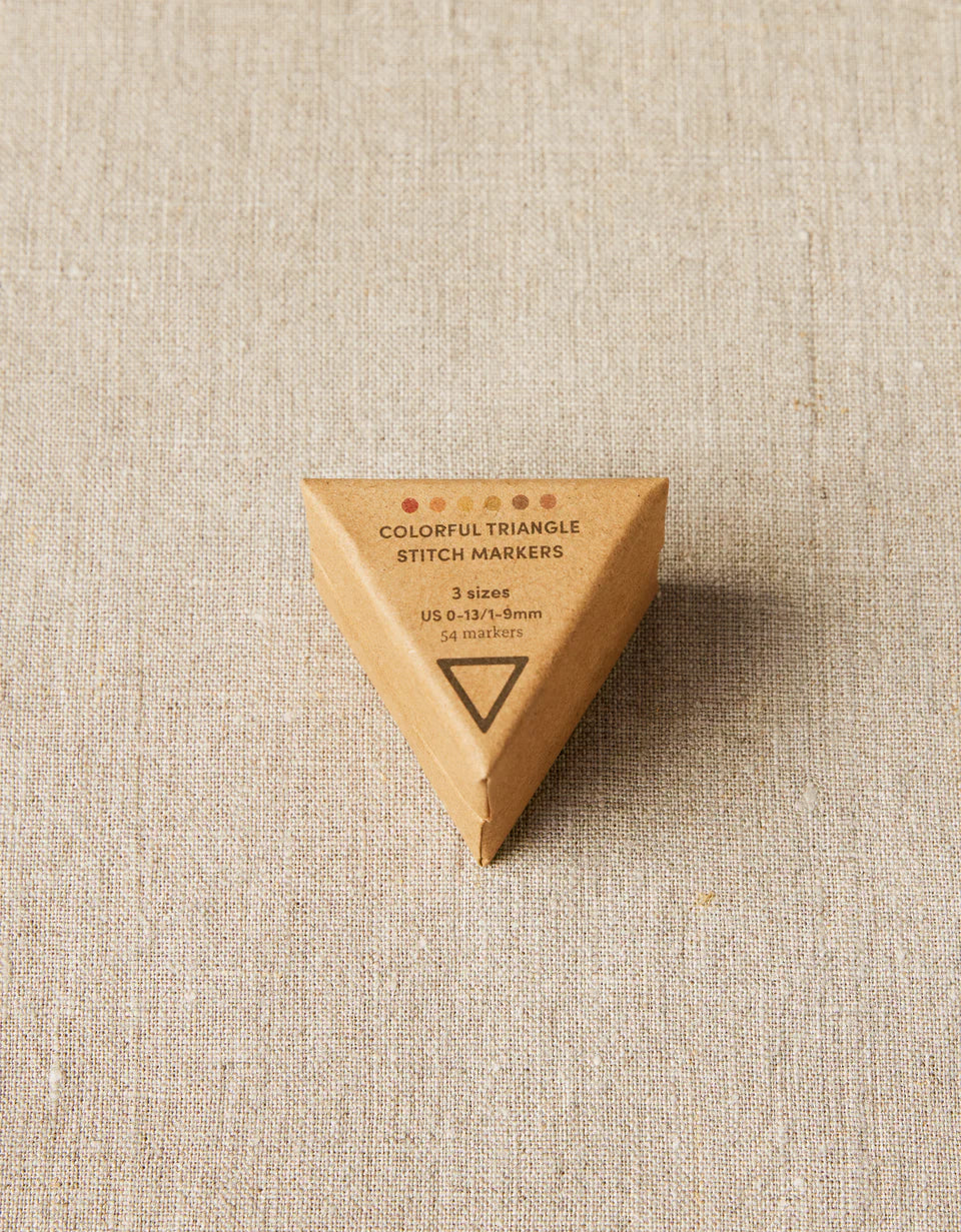 Triangular wooden container with 'Colorful Triangle Stitch Markers' text on a beige fabric background