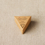 Triangular wooden container with 'Colorful Triangle Stitch Markers' text on a beige fabric background