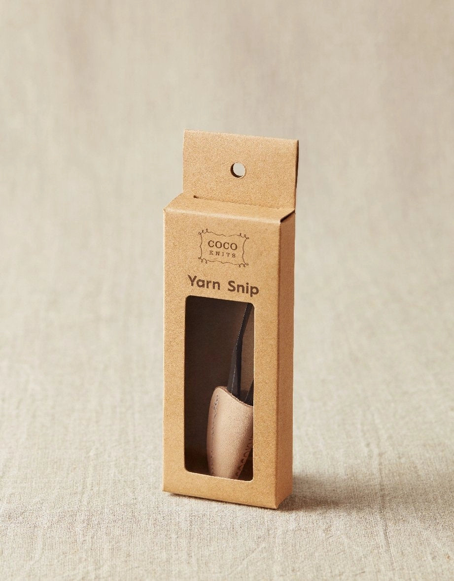 Kraft paper packaging for a yarn snip tool on a beige background