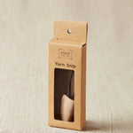 Kraft paper packaging for a yarn snip tool on a beige background