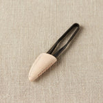Black thread snips inside a leather case on a beige fabric background