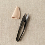 Black yarn snips and beige leather case on a beige fabric background