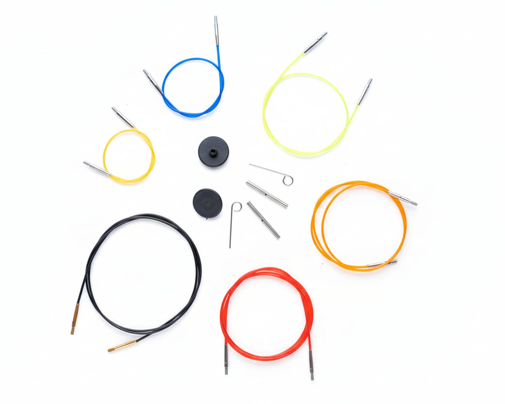 Set of colorful knitting needles and cable on a textured white background